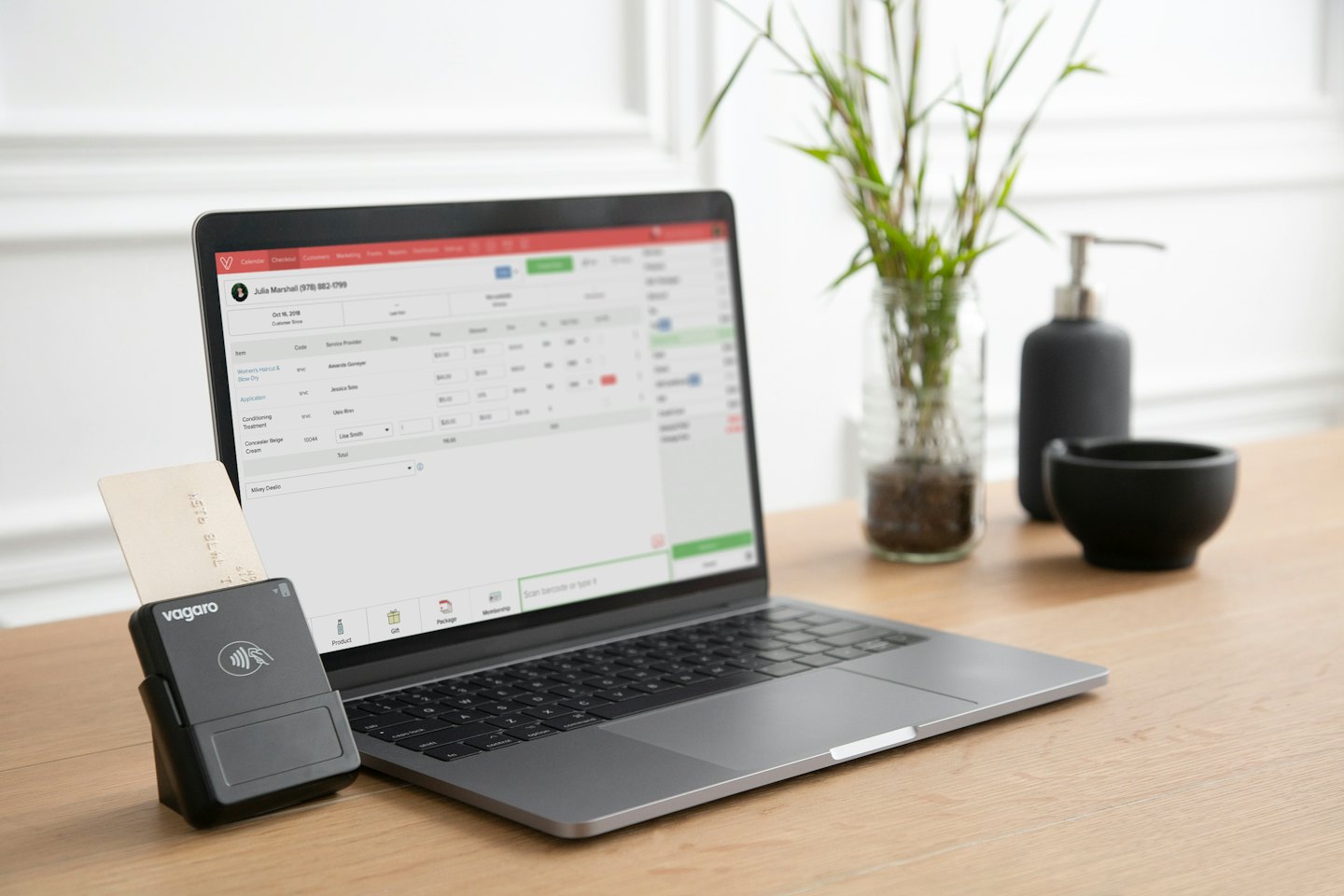Computer portatile con software di pianificazione e lettore di carte di credito su una scrivania.